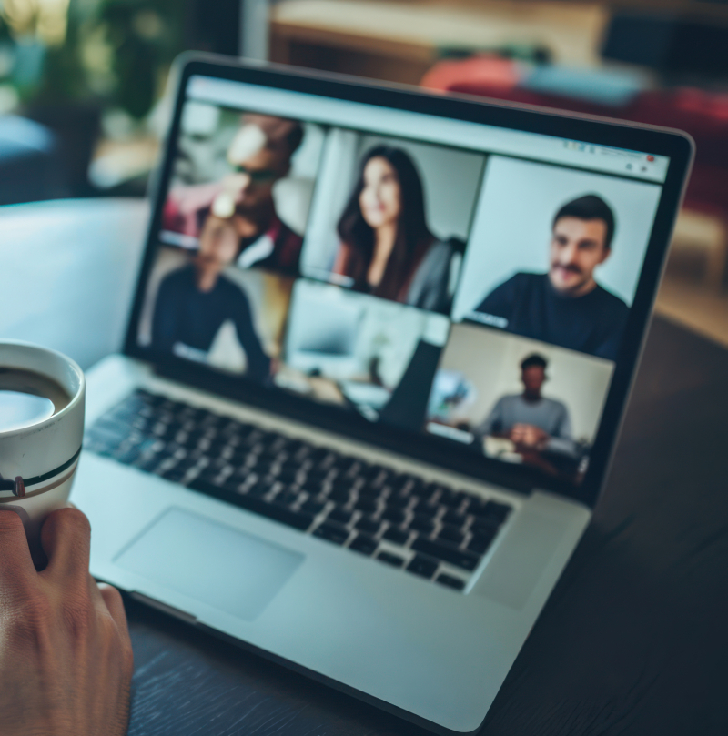 Imagem de uma reuniao online com a presença de várias pessoas. Vê-se o monitor do ecrã e o orador esta a beber um cafe